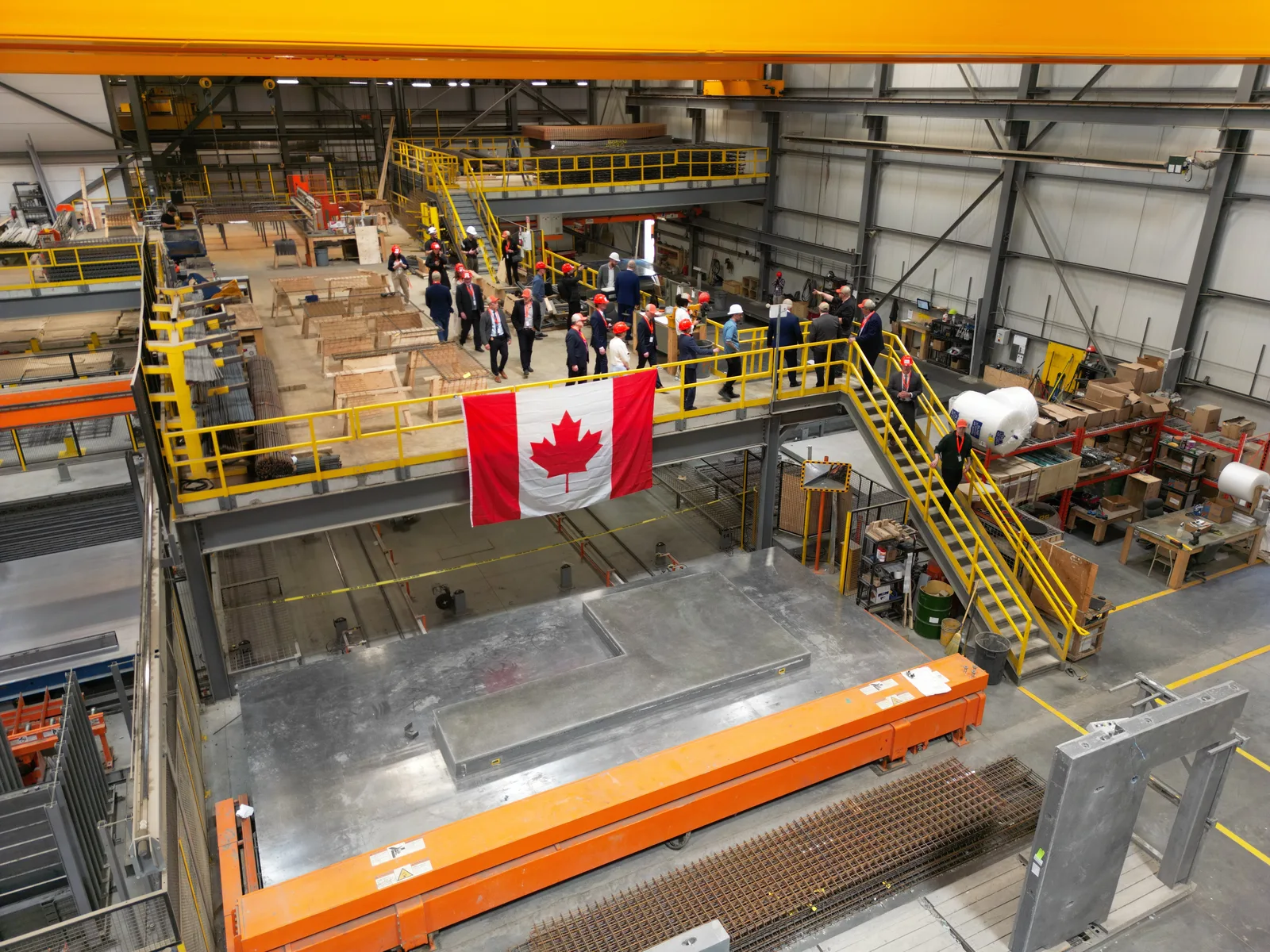 Elevated view of Kiwi Newton’s precast manufacturing facility, with production equipment, visitors and a Canadian flag.