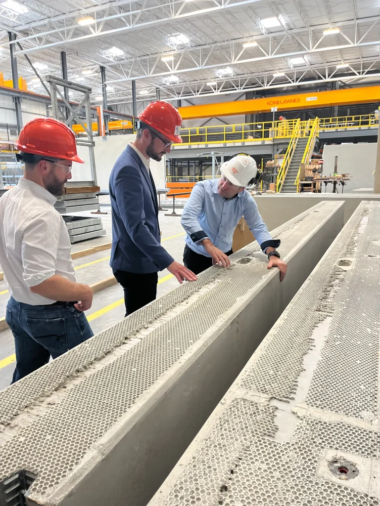 People inspecting a precast component in a manufacturing facility.